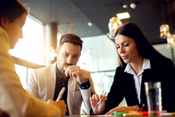Business partners working on new startup business plan, making calculations at meeting in modern office.