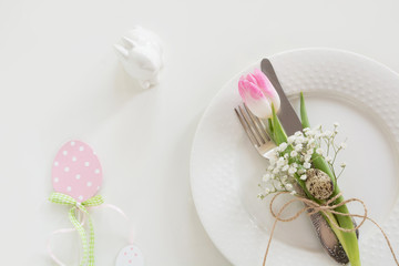 Easter table setting with pink ribbon and tulip on white background. Spring romantic dinner. Top view and copy space for your text.
