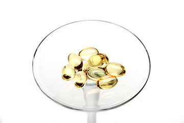 Capsules of cod-liver oil on glass stem isolated on white