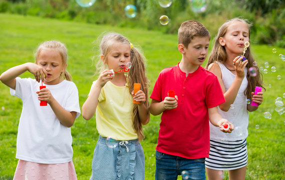 children blowing bubbles in park.