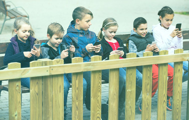 Outdoor portrait of girls and boys playing with phones