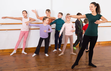 Fototapeta na wymiar assiduous boys and girls rehearsing ballet dance in studio