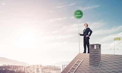 Businessman in suit on house top with ecology concept signboard.