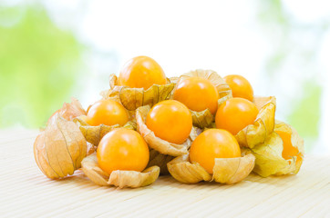 Fresh pichuberry (Cape Gooseberry), very delicious and healthy berry fruit, uchuva on light bamboo mat with nature light green bokeh background in the garden or farm