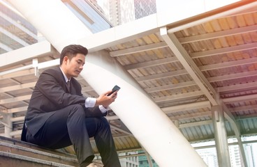 Man is thinking of girlfriend. He is looking at the smart phone.