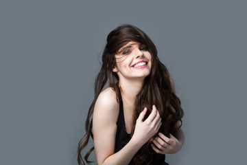 Smiling happy woman with long hair on a gray background.