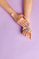 Women's manicure on purple background.