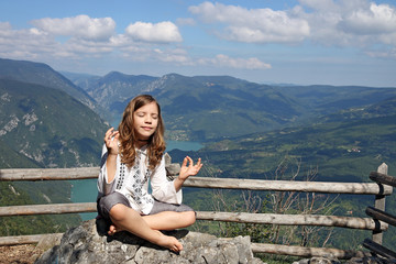 Fototapeta na wymiar beautiful little girl meditating on a mountain top