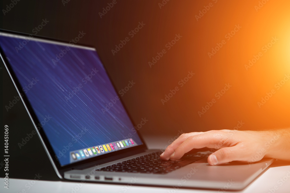 Wall mural hand typing on a keyboard of laptop with operating system screen on background