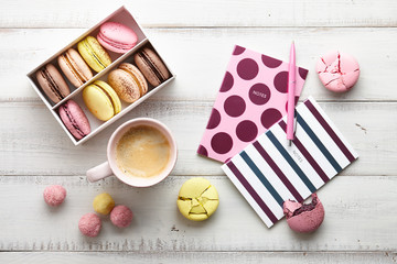 Woman's flat lay workspace with coffee, notebooks and macarons