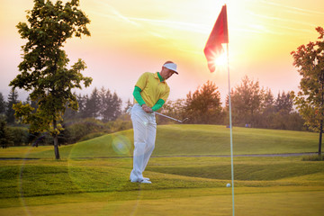 Man playing golf against colorful sunset