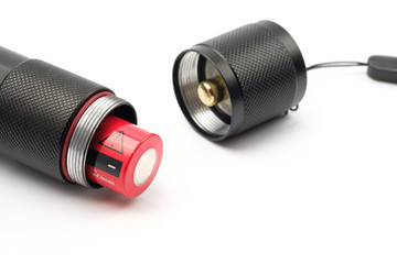 black flashlight opening the tail cap and have red alkaline battery inside on white background