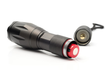 black flashlight opening the tail cap and have red alkaline battery inside on white background