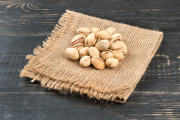 Salted pistachio nuts on burlap and table