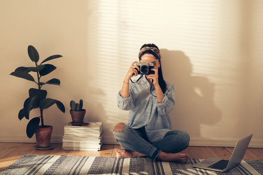 Young woman taking a photograph at home