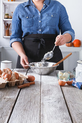 Woman baker stir dough with eggs, butter and flour