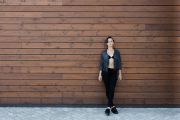 Girl in a black leather jacket near the wooden wall