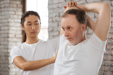 Concentrated bearded man stretching his arms