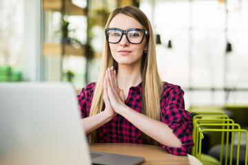 Young woman meditating sitting at the modern office desk in front of laptop, taking a pause, busy,...