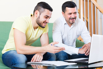 Two men with laptop at home