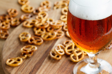 Glass of cold foamy beer with german pretzel