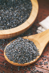 Dry poppy seeds in wooden spoon on table