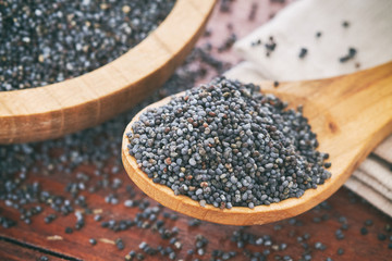 Dry poppy seeds in wooden spoon on table