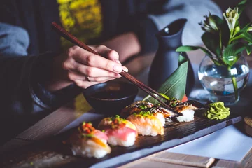 Fotobehang Man eten sushi set met stokjes op restaurant © stockmelnyk