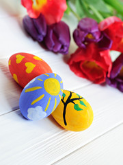 Hand made painted Easter eggs and tulips on white wooden background