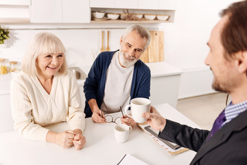 Smiling advisor enjoying conversation with aging couple of clients