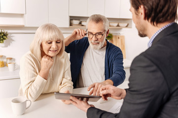 Cheerful retired couple using gadget with real estate agent
