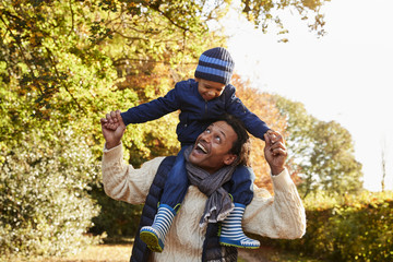 Autumn Walk With Father Carrying Son On Shoulders