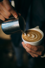 Barista drawing on a latte in a white cup
