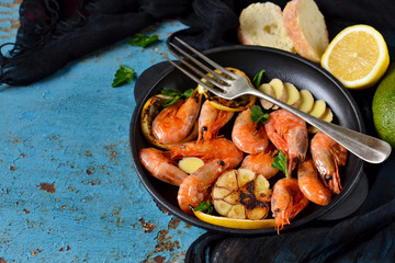 Fried tiger shrimps with garlic and lemon sauce on a cast-iron frying pan