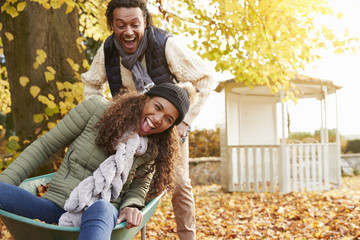 Man In Autumn Garden Gives Woman Ride In Wheelbarrow