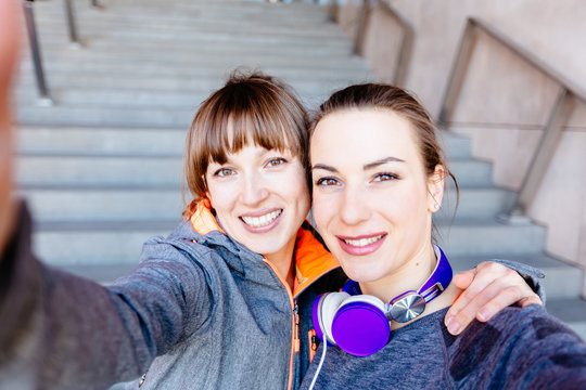 Two sporty women face to face doing selfie after marathon or workout fitness.