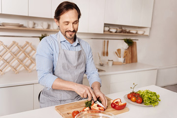 Delighted cook cutting pepper for dinner in the kitchen