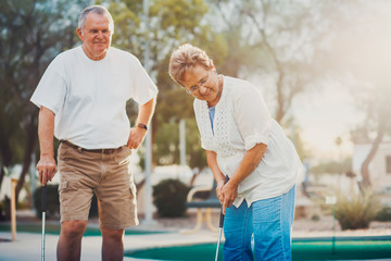 retired married elderly couple playing mini golf together