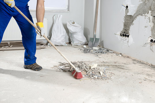 Manual Worker Sweeping Rough Rubble At Construction Site Using Broom.  