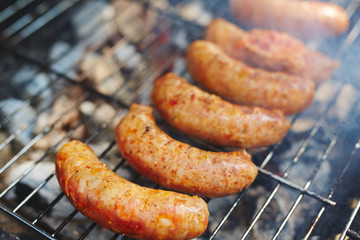 Sausages frying on grill grate during picnic