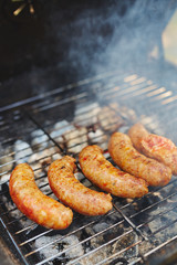 Row of sausages being roasted on fire for picnic table