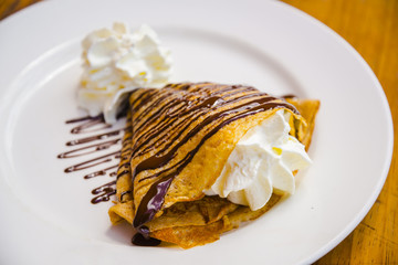Delicious yummy crepe filled with cream and chocolate syrup topping