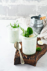 Two glasses of healthy yogurt with a variety of herbs, spinach, dill, onions, parsley and quail eggs. The concept of a healthy vegetarian breakfast. Selective focus.