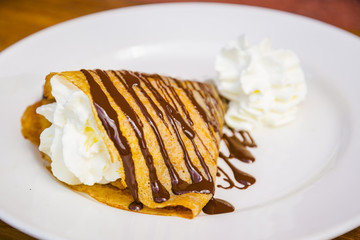 Delicious yummy crepe filled with cream and chocolate syrup topping