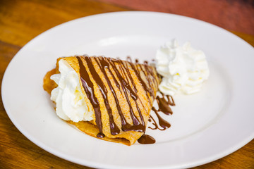 Delicious yummy crepe filled with cream and chocolate syrup topping