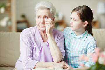 Girl looking at her grandmother wiping tears