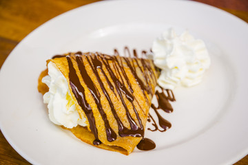 Delicious yummy crepe filled with cream and chocolate syrup topping