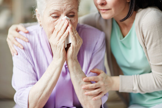 Elderly woman crying and young female embracing her
