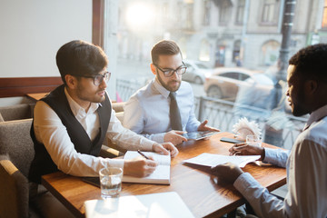 Two men listening to their parner and reading contract shown by him