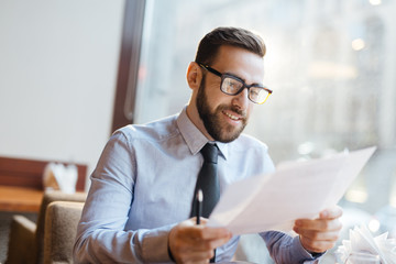 Successful businessman reading papers in cafe